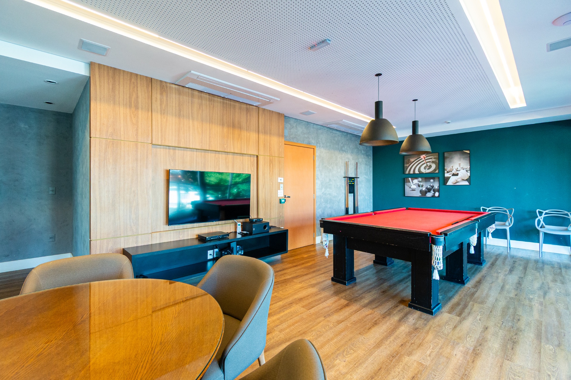 Salão de jogos com mesa de sinuca, home theater e área de convivência